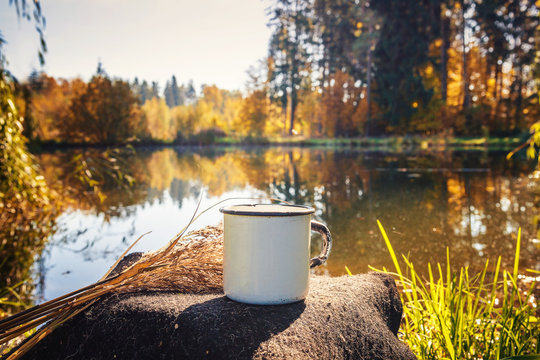 cup of coffee on wood with nature on background. Tourism and travel. Travel thermo mug with brewed tea amid the beautiful lakes 