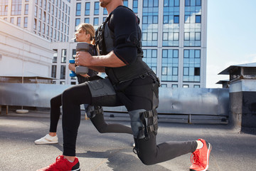 sporty man and woman is using EMS machine. close up cropped photo. copy space.