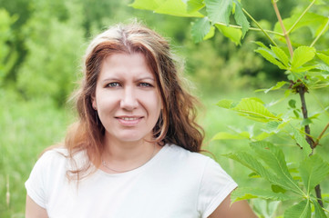 A beautiful middle-aged woman is resting in the park, she is happy because she is going to the hairdresser to paint her hair, which begins to become gray