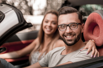 young man with his girlfriend inside a convertible car