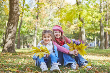 Girl with Down syndrome and little girl in autumn park.