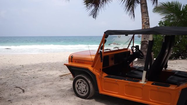 Static view of tropical beach with palm trees and tourist rental car/beach buggy/Moke parked in the shade, Anse Lazio, Praslin, Seychelles. Slow motion 50p.
