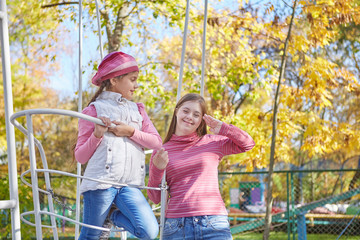 Girl with Down syndrome and little girl in autumn park.