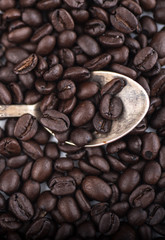 Roasted coffee beans in Old silver vintage dessert  spoon on brown  coffee beans background. Vertical orientation and Top view, Close up.
