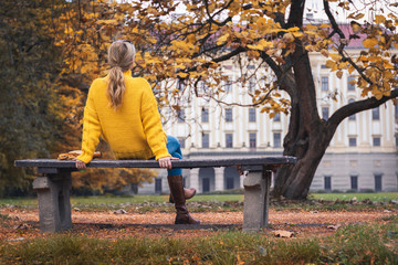 Woman relaxing on park bench at autumn season and looking to castle, Kromeriz, Czech Republic