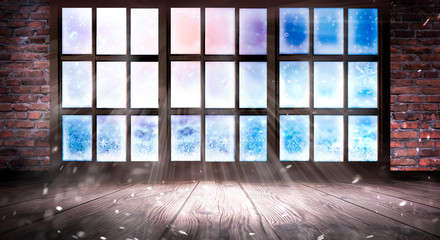 The window is frozen, frosty morning, snowflakes on the glass, an empty room with a window, an old brick wall and a wooden floor. Part of the background is a cozy interior. Sunlight squared frozen win