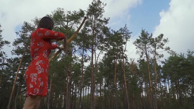 Girl in red dress practice in shooting in forest