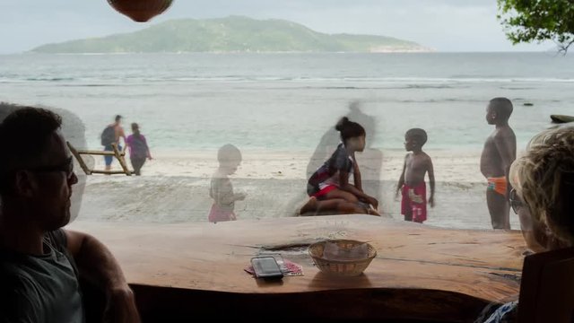 Timelapse of honeymoon couple having lunch (traditional Creole specialities) at beach restaurant, view onto sea Anse Banane, Seychelles. 4K, 25p.