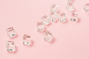 Ice cubes scattered on a light pink background. Flat lay, top vi