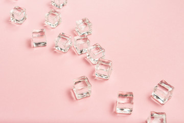 Ice cubes scattered on a light pink background. Flat lay, top vi