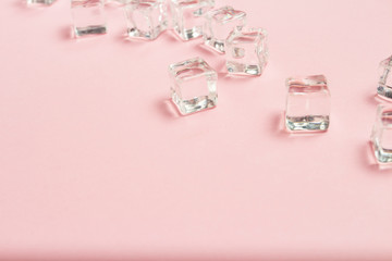Ice cubes scattered on a light pink background. Flat lay, top vi