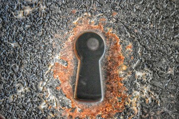 A rusty keyhole in an iron prison door