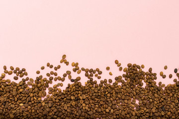 Coffee grains in the bottom of the image on a gently pink backgr
