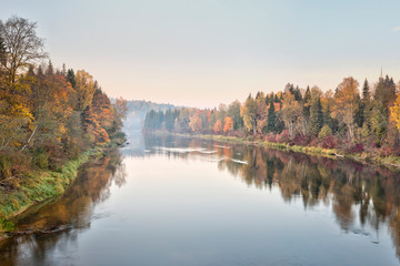 Naklejka na ściany i meble Autumn landscape mysterious foggy morning in a field near the river