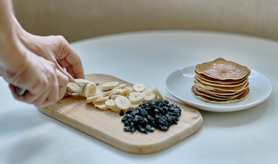 A woman cuts bananas and blue berries