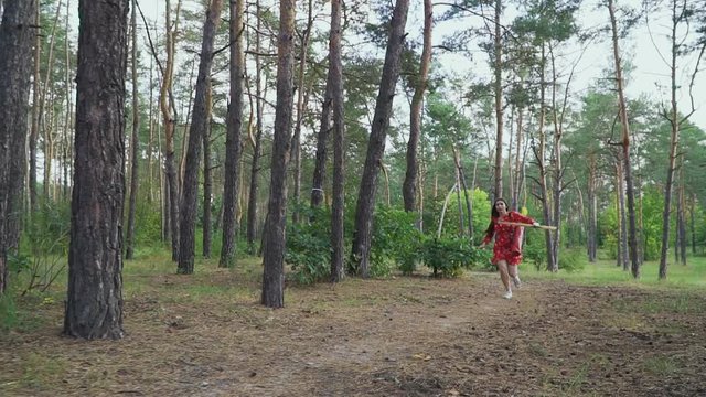 Girl in red dress with bow running cross forest
