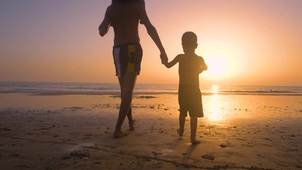 Silhouette of father with two children in the beach at sunset