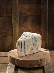 Slice of blue cheese on wooden board on dark background