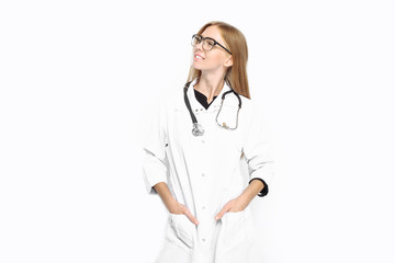 The girl doctor, a trainee in glasses, wearing a white coat, with a stethoscope around his neck, smiles happily, on a white background