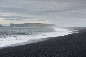 he black sand beach with typical Icelandic mountain landscapes