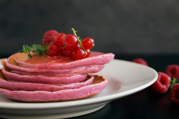 Berry homemade pancakes on a black background.