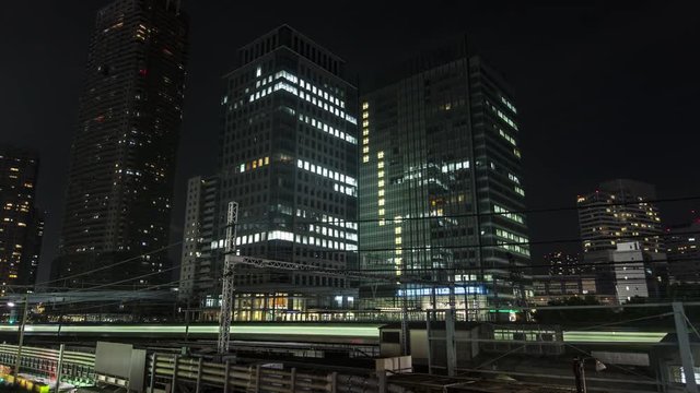 Time Lapse of trains moving at night, modern buildings in background, Tokyo, Japan