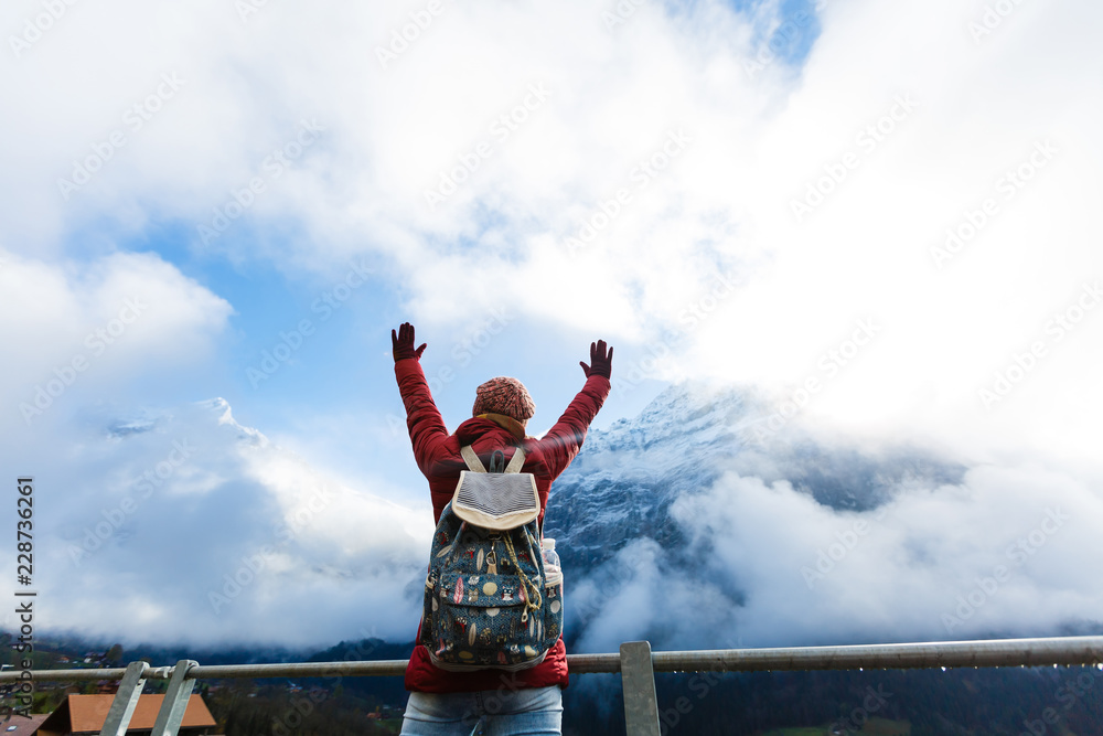 Wall mural a woman tourist excited while looking at a high mountain against a blue sky in the alps, switzerland