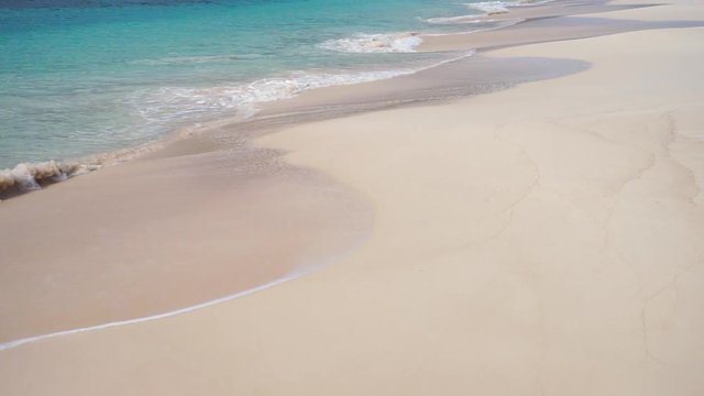 Scenic tropical island beach with white sand, turquoise blue water and waves crashing gently on the sea shore. Seychelles. Slow motion 50p