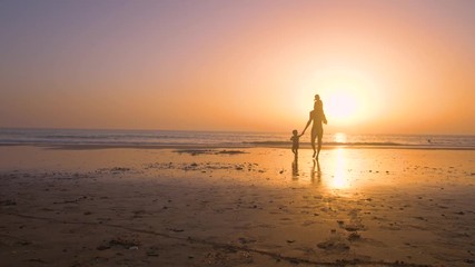 Silhouette of father with two children in the beach at sunset
