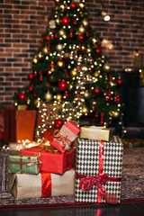 Christmas Gifts wrapped in brown and red paper in loft, background with xmas lights bokeh of blurred Christmas tree. Copy space