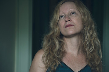 Woman with long reddish blonde wavy hair looking up