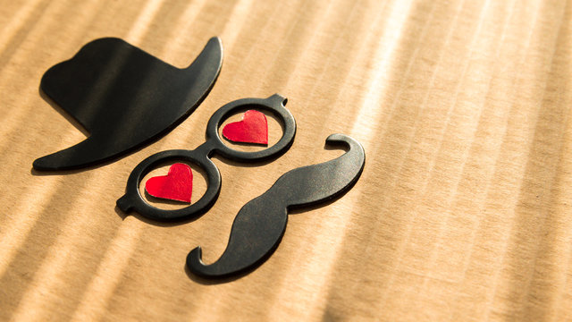 Happy Father's day background or card. sign of black hat, mustache and pipe with two red heart - eyes with glasses. empty copy space for inscription. close-up