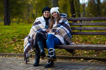 Portrait of happy mother with adult daughter covered with blanket in autumn park