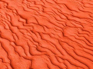 texture of red sand waves on the beach or in the desert. the ripples of the sand is diagonal.