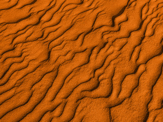 texture of yellow red sand waves on the beach or in the desert. the ripples of the sand is diagonal.