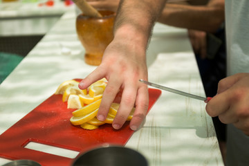 Obraz na płótnie Canvas cropped view of man cutting yellow lemons Man slicing lemons in the kitchen. Picnic