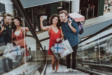 Couple with Packages Taking Selfie on Escalator.