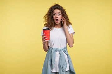 woman speaking by the smartphone and holding a cup of coffee,