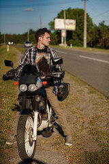 Fototapeta na wymiar A biker stands near his motorbike. Attractive young man at his bike.