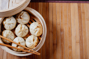 Steamed dumplings Dim Sum in bamboo steamer on bamboo wooden background. Chinese food
