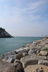 Scogli mare e barca a vela con cielo azzurro
