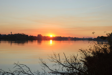 Autumn nature. Landscape of sunrise over river in autumn foggy morning. Red foliage falls to ground. Calm Autumn Nature