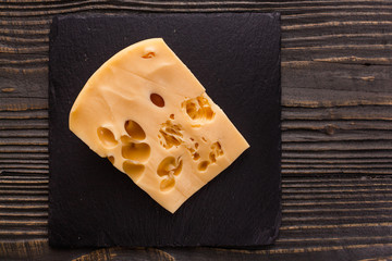 Piece and slices of cheese on a wooden background
