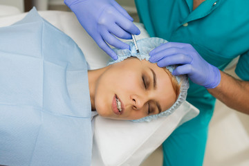 top view of eye augmentation procedure on a young woman done by a cosmetologist doctor with Hyaluronic acid Injection.