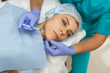Top view of chin augmentation procedure on a young woman done by a cosmetologist doctor with...