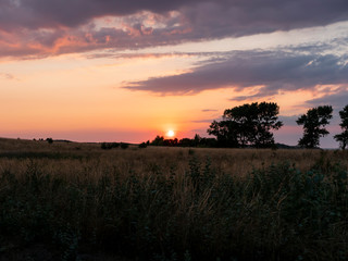 Obraz na płótnie Canvas Sun setting over the savannah leaving a purple and orange sky
