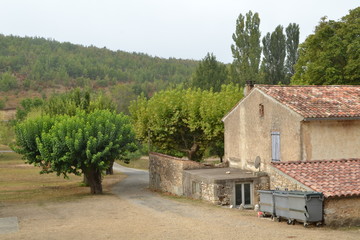 Fototapeta na wymiar zijkant van boerderij in de Provence met schuren, woonhuis, oprijlaan en vuilnisbakken