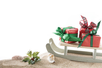 Winter seasonal gift boxes with bow and slide on sand, with white background and copy space.