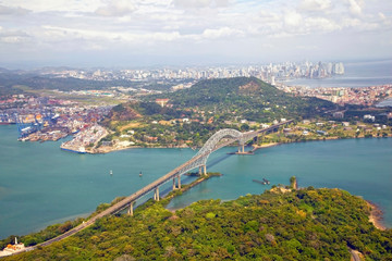 Aerial view of the Bridge of the Americas at the Pacific entrance to the Panama Canal with Panama City in the background. - obrazy, fototapety, plakaty