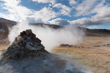 Fototapeta na wymiar Smoking fumarole near Hverir geothermal area, Myvatn Lake area, Iceland. Geothermal area with smoking fumaroles and mud geothermal springs in Namskard geothermal area, Iceland, Europe
